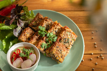 Photo of hot delicious deep fried minced pork toast menu dish with sweet and sour sauce on wooden table background. Eatable food appetizer recipe local international Thai food herb for concept ideas