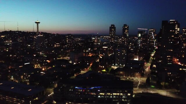 Drone dolly in over downtown Seattle Washington with Space Needle on the right at twilight in the night