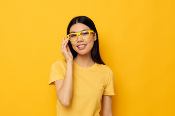 woman with Asian appearance in yellow t-shirts with glasses posing fashion yellow background unaltered