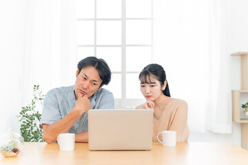 ノートパソコンを見る夫婦（困る）
