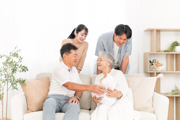 Obraz premium 赤ちゃんを抱いた老夫婦と若い夫婦（里帰り） 