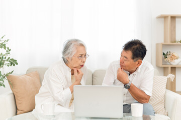 ノートパソコンを見る高齢者夫婦（困る）
