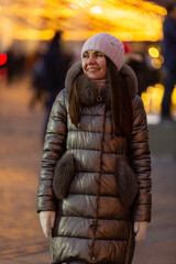 A young woman stands on a festive decorated street and smiles away, Christmas and New Year holidays