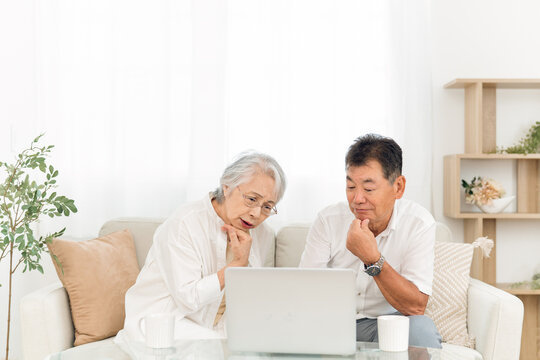 ノートパソコンを見る高齢者夫婦（困る）
