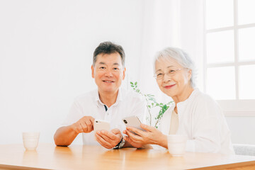 スマホを使う高齢者夫婦（笑顔）
