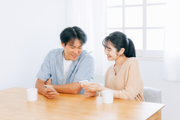スマホを見る夫婦（笑顔）
