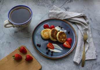 close up of Healthy and delicous breakfast with cottage cheese pancakes, strawberries and sour cream on dark blue plate