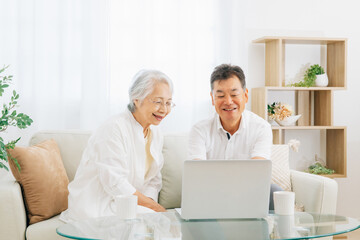 ノートパソコンを見る高齢者夫婦（笑顔）
