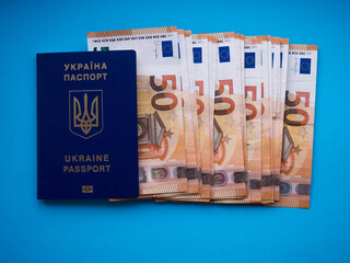 A set of European Union money with a face value of 50 euros on blue background. Background of the fifty euros banknotes and Ukraine passport with copy space. Finance, savings and travel concept