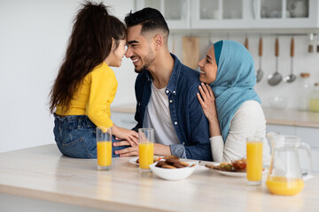 Happy Young Middle Eastern Parents Bonding With Their Little Daughter In Kitchen