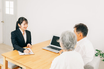 Fototapeta premium パソコンで説明するスーツ姿の女性と高齢者夫婦 