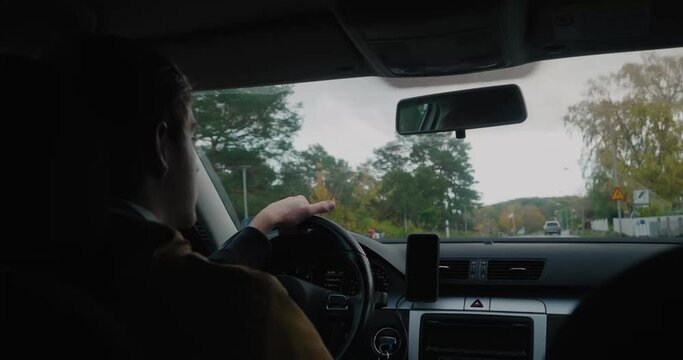 Young Man Drives On a Country Road With Houses and Trees in Fall, Simrishamn Sweden - Handheld Medium OTS Shot