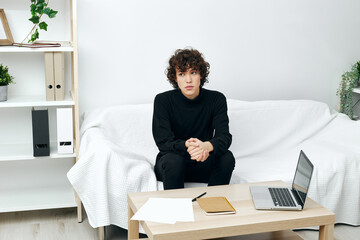 teenager sitting on the couch at the table in front of a laptop communication