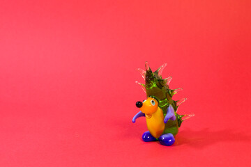Miniature glass hedgehog figurine isolated on red background
