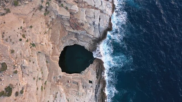 Above aerial view of Giola natural pool near the Mediterranean seaside. Waves crushing the shoreline. Thassos island, Greece