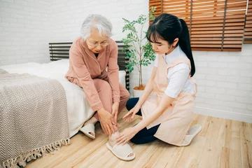 Fotobehang 痛がる高齢者女性と介護士（足首） © buritora