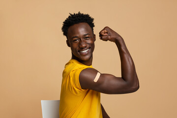 Happy Black Guy Showing Arm With Adhesive Bandage After Covid-19 Vaccination Shot - obrazy, fototapety, plakaty