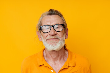 an elderly man with glasses in a yellow t-shirt with glasses close-up