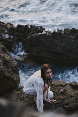 woman sitting on stones in a white dress wet hair top view