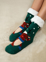 Women's feet  on the bed in warm christmas socks. cropped image