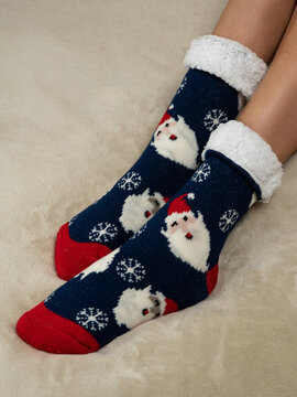 Women's feet  on the bed in warm christmas socks. cropped image