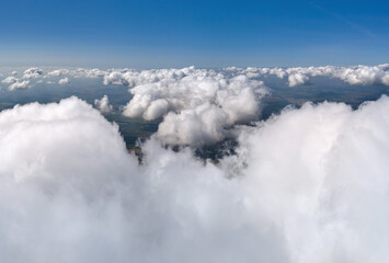 Aerial view from airplane window at high altitude of earth covered with puffy cumulus clouds...