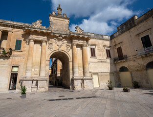 Fototapeta premium Lecce, Puglia, Italy. August 2021. View towards one of the access gates to the historic center. People enter and leave the old city through it. Beautiful summer day.