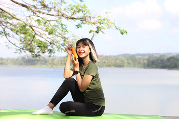 Smiling asian woman holding carrot in front of river