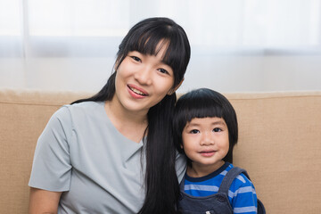 Mother and little boy sitting living room at home happy family moment smiling to camera.