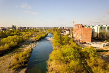 Obraz premium Aerial view of tall residential apartment buildings under construction and Bystrytsia river in Ivano-Frankivsk city, Ukraine.