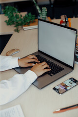 Fototapeta premium Woman typing at laptop keyboard on desk