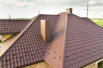 Detail view of house rooftop covered with brown metal tile sheets.