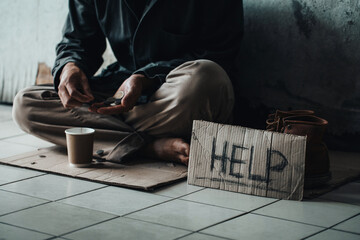  Poor tired depressed hungry homeless man counting coins with cardboard card with "help" handwritten text. nostalgia and hope concept.