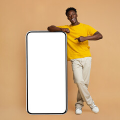 Happy Black Man Leaning And Pointing At Big Smartphone With White Screen