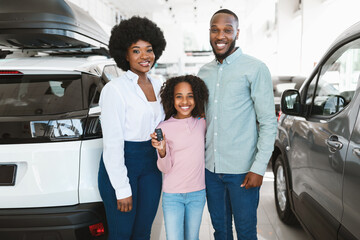 Fototapeta Portrait of happy black family with car key smiling at camera, buying new vehicle in auto dealership obraz