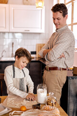 Fototapeta na wymiar lovely family in bright modern kitchen. Father and child son baking cookies, x-mas celebration. handsome caucasian adult male looking at process of making tasty delicious cookies by son