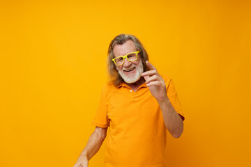 Senior grey-haired man yellow t-shirt and glasses posing yellow background