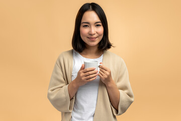 Delighted young asian ethnic woman in domestic wear smiling and looking at camera
