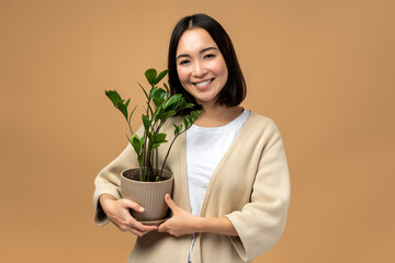 Woman in cozy outfit holding plant on beige background