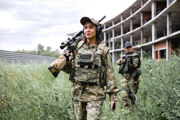two strong ladies in tactical gear going in field, preparing for fight, war. Caucasian Military...