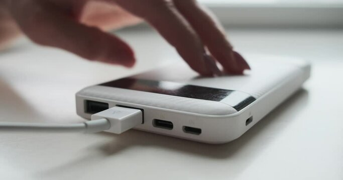 Woman connecting usb cable to powerbank on desk