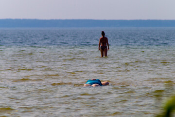 Overweight woman in swimsuit lying in a water. Vacation on lake beach