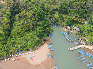 Aerial view of Baron beach in Yogyakarta, Indonesia with lighthouse and traditional boats