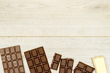 milk and black, white chocolate bars on wood table