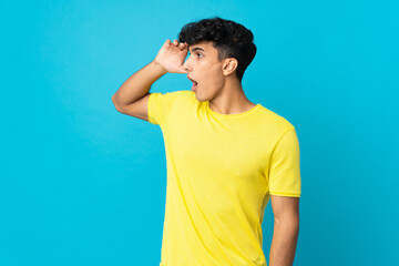 Young Argentinian man isolated on background with surprise expression while looking side