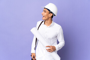 Young architect man isolated on background laughing in lateral position