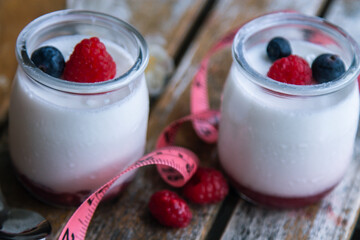 yogurt with wild berries and measuring tape. diet and eating concept