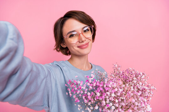Self-portrait of attractive cheerful nice girl holding gypsophila good mood isolated over pink pastel color background