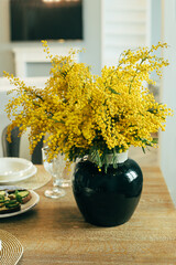 Bouquet of yellow mimosa flowers in a glass vase on awooden table. 8 March, women's day concept. - 480332675