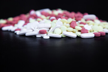 Tablets of different colors on a black background.